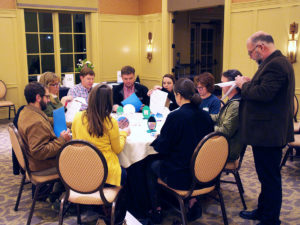 group of people sitting at a table during a Sage School outreach event
